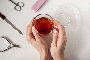 Karantinada eski manikürlü bir kızın elleri. Manikür yap, çay iç, evde kal. Soyulmuş, pejmürde jel cilası..