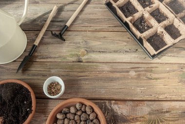Taklit uzay ev bahçesi ahşap bir masada. Tohumlar, turba kapları, toprak, genişletilmiş kil ve küçük bahçe aletleri. Pencere kenarındaki bahçe..