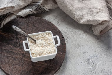 Kare bir kasede hindistan cevizi gevrekleri beton bir masa arkasında tahta bir tahtanın sapları var. Mutfak kapağı, malzeme.