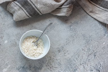 Yuvarlak bir kasede yuvarlak hindistan cevizi taneleri beton masa üstü arka planında. Mutfak kapağı, malzeme.