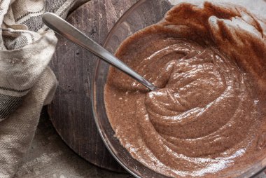 Cam kasede kaplumbağa keki için hamur. Koyu ahşap bir tahtanın üzerinde gri beton bir masanın üzerinde bej bir havlunun yanında. Pişirme işlemi.