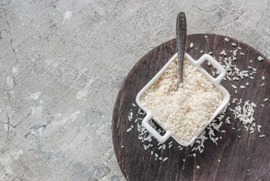 Kare bir kasede hindistan cevizi gevrekleri beton bir masa arkasında tahta bir tahtanın sapları var. Mutfak kapağı, malzeme.