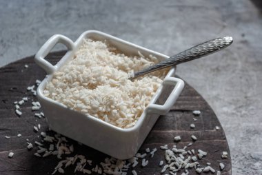 Kare bir kasede hindistan cevizi gevrekleri beton bir masa arkasında tahta bir tahtanın sapları var. Mutfak kapağı, malzeme.