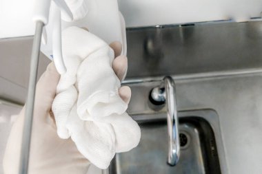 Alkol ve dezenfektan dağıtıcısı. Enfeksiyon koruması. Elinde tıbbi eldiven ve tek kullanımlık ameliyat elbisesi olan bir gazlı bez..