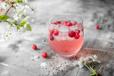 Çiçekler ve yapraklarla bembeyaz bir masada buzlu yaban mersinli limonata.