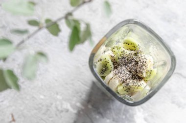 Cam karıştırıcıya dilimlenmiş meyve püresi malzemeleri: muz, kivi ve chia tohumu. Sağlıklı ve lezzetli kahvaltı tarifi.
