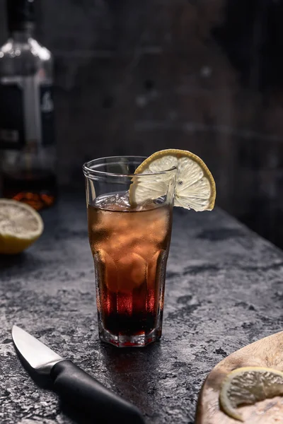 Kola dolu buzla dolu bir bardak rom ve karanlık bir tarlada bir dilim limon. Alkolik kokteyl.