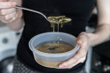Yumuşak odaklanma. Kız plastik bir kutudan miso çorbası içiyor. Sıcak yemek..