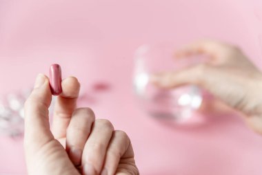 Yumuşak odaklı kız elinde pembe arka planda bir ilaç kapsülü tutuyor. Sağlık Hizmetleri Ortak Alanı