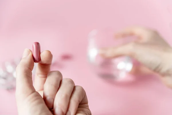 Yumuşak odaklı kız elinde pembe arka planda bir ilaç kapsülü tutuyor. Sağlık Hizmetleri Ortak Alanı