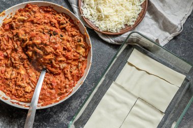 Ev yapımı lazanya pişirme işlemi: Bolonez ve rendelenmiş peyniri fırın tabağına koy.