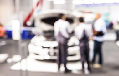 Soyut insanlar arka planda bulanık otomobil sergileriyle iletişime geçiyorlar