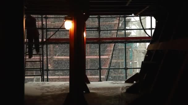 Silhouette eines Arbeiters auf einer Baustelle mit Schneehintergrund — Stockvideo