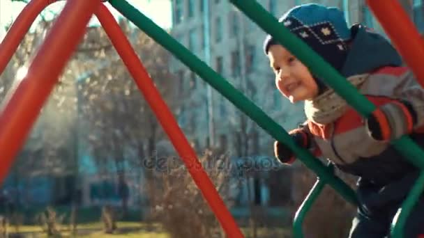 Riant petit garçon chevauchant une balançoire — Video