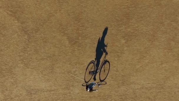 Ombre de vélo et cavalier se déplace lentement dans le parc. Vue inhabituelle du haut . — Video