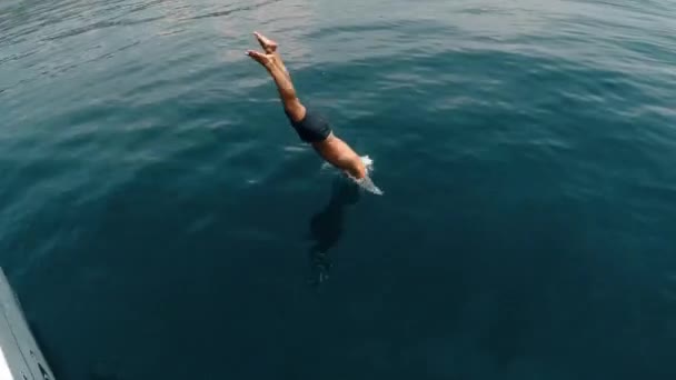 Turistické muž skákat z jachty ve vodě — Stock video