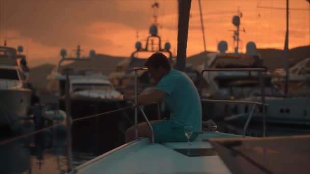 Triste homem bonito no barco à vela no pôr do sol . — Vídeo de Stock