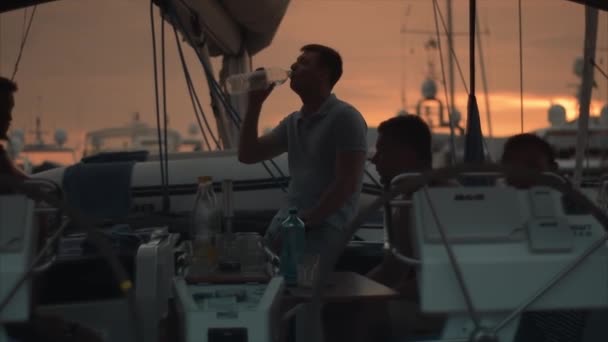 Hombres guapos en barco de vela hablan al atardecer . — Vídeo de stock