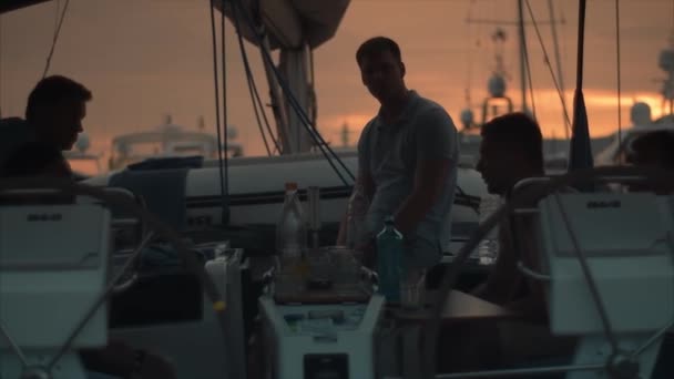 Homens bonitos no barco à vela falar ao pôr do sol . — Vídeo de Stock