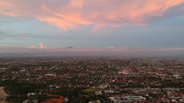 Drönare skytte stad med röda tak och en vulkan i bakgrunden mot en rosa-blå himmel på kvällen — Stockvideo