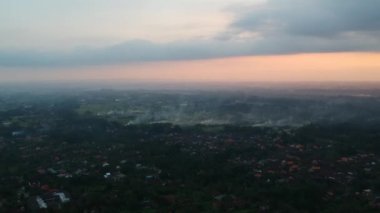 Kuadrokopter Bali 'deki Ubud ormanında uçar, dumanlı yangınlar görünür, ve gün batımına doğru uçar, tüm gökyüzü bulutlarda ve akşam sarı-turuncu güneş görülebilir
