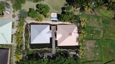 İnsansız hava aracı, Ubud Bali 'de suyla çevrili piramitten çok uzaklara uçuyor açık güneşli havada, palmiye ağaçları ve pirinç tarlalarından oluşan tropikal çalılıklar görülebiliyor.