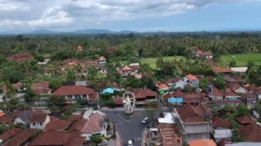 Güneşli havada COK Gede Rai ve Raya Ubud bali kavşağında ArJUNA heykelinin üzerinde uçan arabalar ve scooterlar görülebiliyor.