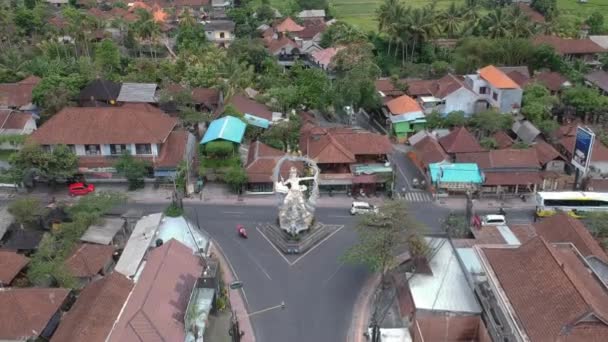 De kruising met het ARJUNA standbeeld toont passerende auto 's en scooters op de kruising van COK Gede Rai en Raya Ubud bali bij zonnig weer — Stockvideo