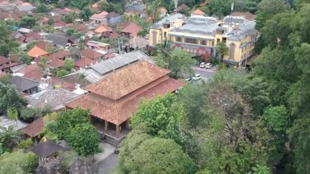 Vliegen over de Balinese tempel Pura Dalem Puri Peliatan-Ubud gelegen in het centrum van Ubud in de tropische jungle en aankomen bij een modern gebouw — Stockvideo