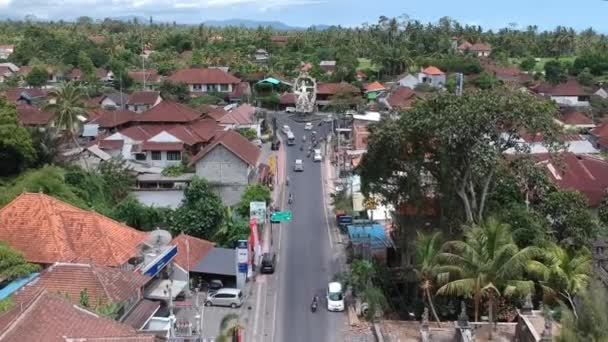 Volant au-dessus de la statue d'ARJUNA, les voitures et scooters de passage sont visibles à l'intersection de COK Gede Rai et Raya Ubud bali par temps ensoleillé — Video