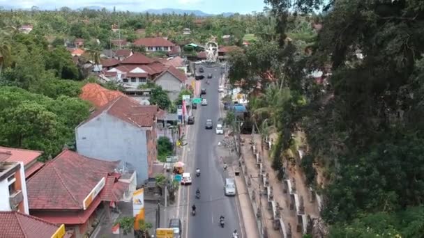 Fliegen über die ARJUNA-Statue, vorbeifahrende Autos und Motorroller sind bei sonnigem Wetter an der Kreuzung von COK Gede Rai und Raya Ubud bali zu sehen — Stockvideo