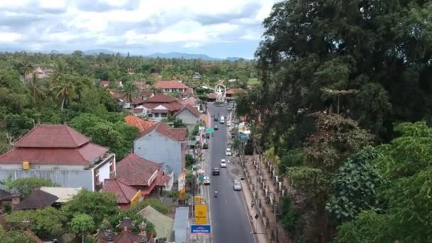 在阳光明媚的天气里，在科克吉德拉伊和拉亚乌布巴利的交汇处，可以看到在乌布德经过的汽车和摩托车中间的Pura Dalem Temple Puri Peliatan-Ubud旁边飞行 — 图库视频影像