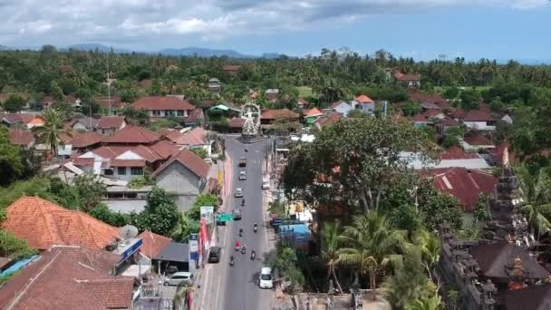 Volando junto al Templo Pura Dalem Puri Peliatan-Ubud situado en el centro de Ubud en la selva tropical a lo largo de una carretera concurrida coches scooters — Vídeos de Stock