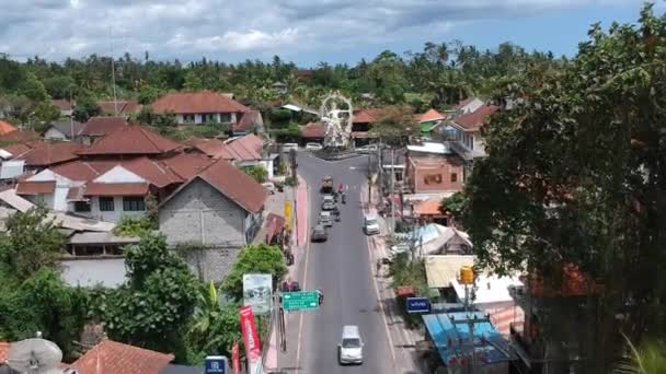 Vliegen naast de Pura Dalem Tempel Puri Peliatan-Ubud gelegen in het centrum van Ubud in de tropische jungle langs een drukke auto scooters — Stockvideo