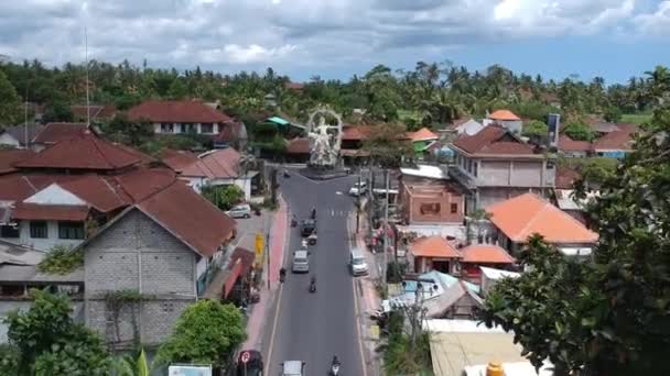 Vliegen naast de Pura Dalem Tempel Puri Peliatan-Ubud gelegen in het centrum van Ubud in de tropische jungle langs een drukke auto scooters — Stockvideo
