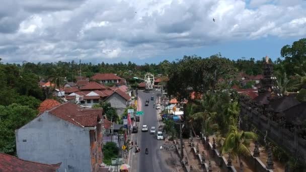 Статуя Арджуна, проезжающие машины и скутеры видны на пересечении Кок Геде Рай и Рая Убуд Бали в солнечную погоду — стоковое видео