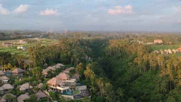 Vuelo al atardecer sobre Ubud durante una pintoresca puesta de sol, un hotel caro es visible a lo largo del lecho del río en Ubud — Vídeos de Stock