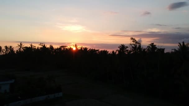 Απογείωση προς το ηλιοβασίλεμα πάνω από ubud κατά τη διάρκεια ενός γραφικού ηλιοβασιλέματος, σε μεγάλο ύψος, ο κόκκινος κύκλος του ήλιου είναι ορατός μέσα από τα σύννεφα — Αρχείο Βίντεο