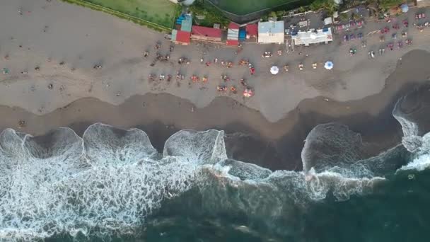 Take off from the ocean with big waves and people sunbathing under umbrellas — Stock Video