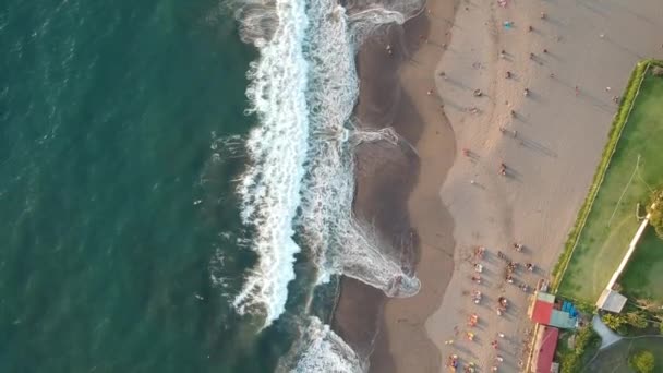 Летать над океаном во время заката и люди загорают у воды с большими волнами — стоковое видео