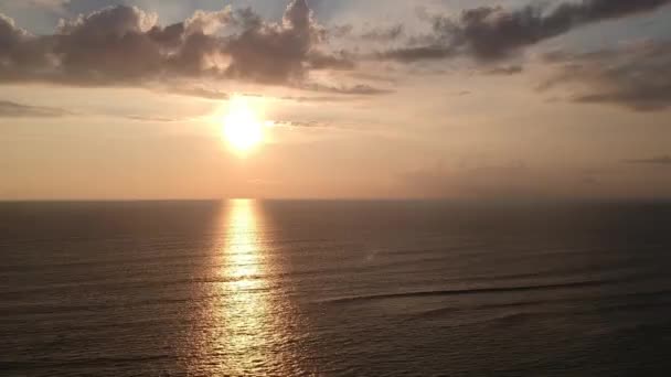 Nedgång av en drönare vid solnedgången på bakgrunden av havet med en gyllene stig, rosa-blå himmel och vackra moln — Stockvideo
