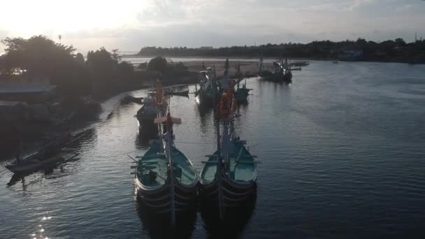 Багато традиційних балійських човнів на тлі гавані і річки, що впадає в океан Пранкак Перенчак на заході балі при заході сонця. — стокове відео