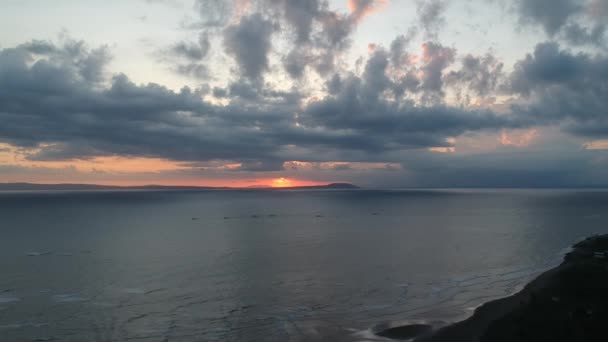 Un dron volando sobre el océano durante la puesta del sol con el gran sol rojo Prancak Perancak barcos de pesca visibles en la distancia — Vídeos de Stock