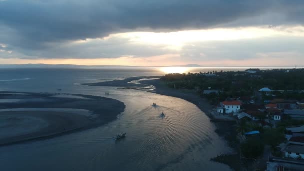 Drönare docka över havet där båtar seglar mot solnedgången och många moln Prancak Perancak halvön Bali indonesien — Stockvideo