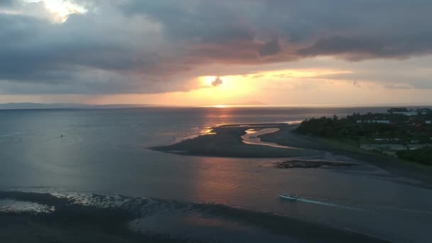 壮大な夕日から飛んでいく姿は、プランカク・ペランカク半島・バリ・インドネシアの港で浮かび上がっています — ストック動画