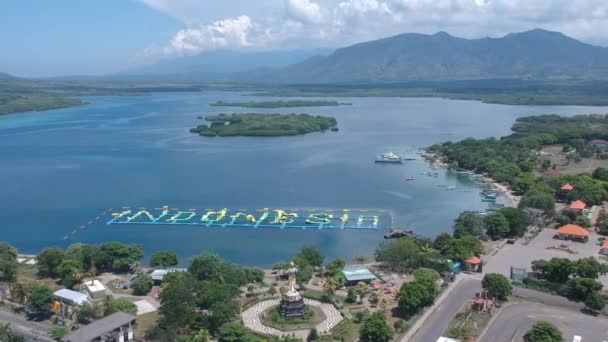 无人驾驶飞机飞越湿婆纪念碑塔曼西瓦和一个巨大的题词印度尼西亚在阳光灿烂的天气与大海和山脉吉里马努克梅拉雅西巴里印度尼西亚 — 图库视频影像