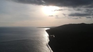 Okyanusun yarısının ve karanın yarısının üzerinde güneşli havada bulutlu mavimsi bir gökyüzüne karşı uçuyor Padang bai limanı bali Endonezya