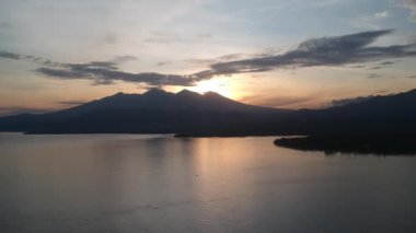 Lombok Pulau adasındaki bir volkanın arka planına inen Lombok Batı Nusa Tenggara balıkçı tekneleri şafakta görülebilir.