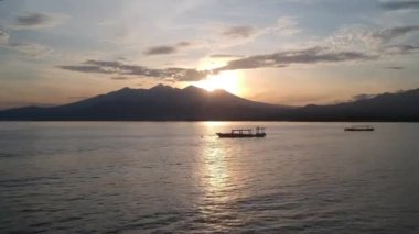 Şafak vakti Lombok Pulau Lombok Batı Nusa Tenggara adasındaki bir volkanın arka planında balıkçı teknelerinin üzerinden uçmak