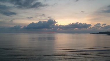 Okyanusa iniyor ve gün batımında pembe çiçeklerle dalgalanıyor.